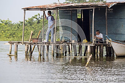 Fisher men sitting in poor wooden houses lifted up on Maracaibo Editorial Stock Photo