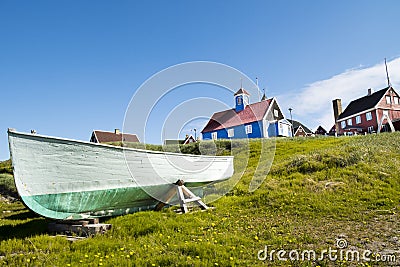 Fisherboat Sisimiut, Greenland. Colorful wooden boat on green summer meadow with wooden colorful houses Stock Photo