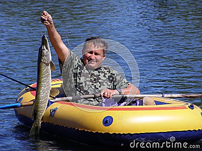 The fisherman in the boat with a pike Stock Photo