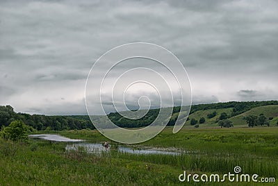 Fisherman in a boat on a small lake in a cloudy hilly valley Stock Photo