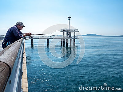 Fisherman on the bridge with a pier and jumping and walking people in Burgas, Bulgaria Editorial Stock Photo