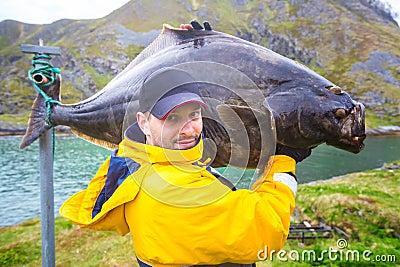 fisherman carries on his shoulder a huge fish. 25 kg halibut. Stock Photo