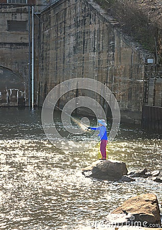 A fisherman casting behind a large dam. Editorial Stock Photo