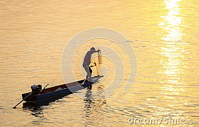 ``Fisherman casts his net from a small boat at sunset,on the Mekong river,in southern Laos Editorial Stock Photo