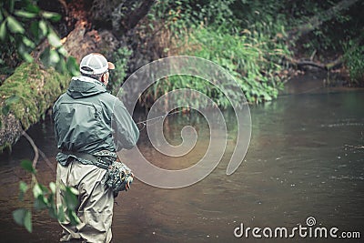 A fisherman catches spinning in the waders. Trout fishing Stock Photo