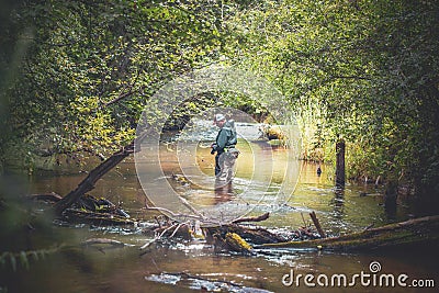 A fisherman catches spinning in the waders. Trout fishing Stock Photo