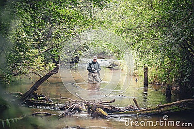 A fisherman catches spinning in the waders. Trout fishing Stock Photo