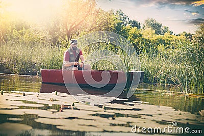 Fisherman caught a fish. A man in a fishing boat in lake. Stock Photo