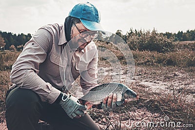 Fisherman caught and holds a carp in his hands Stock Photo