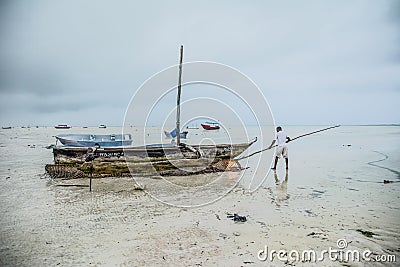 Fisherman cleaning his boat. Zanzibar. Tanzania Editorial Stock Photo