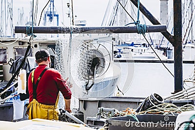 Fisherman cleaning and storing fishing nets after fishing Editorial Stock Photo