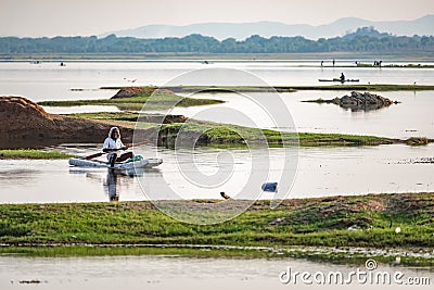 Fisherman coming back to the shore on his makeshift boat on a hazy summer day Editorial Stock Photo