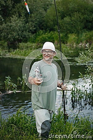 Fisherman with fishing rod near the lake at summer Stock Photo