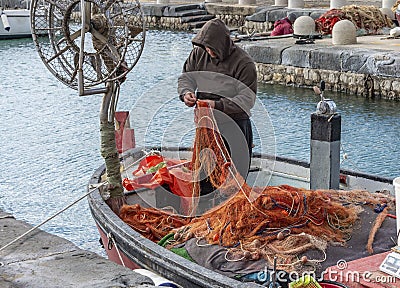 Fisherman fixing the net on the boat Editorial Stock Photo