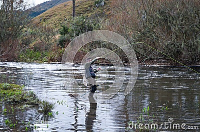 Fisherman fly fishing rainbow trout on mountain in beautiful sce Stock Photo