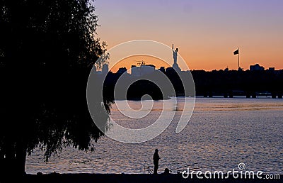 Fisherman in the foreground of the iconic Motherland Mother monument at sunset in Kyiv, Ukraine Editorial Stock Photo