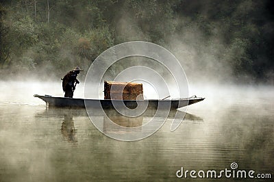 Fisherman and his boat in a misty morning Editorial Stock Photo
