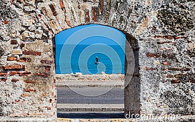 Fisherman on his boat seen through the embrasure of the city walls in the Cartagena Stock Photo