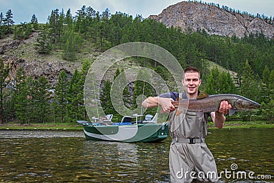 A fisherman holding a taimen trout caught on a river in Mongolia, Moron, Mongolia Stock Photo