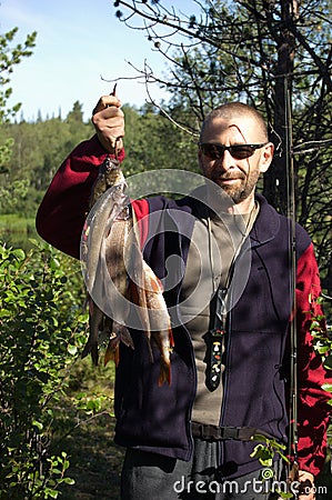 Fisherman holds some graylings and perches. Stock Photo