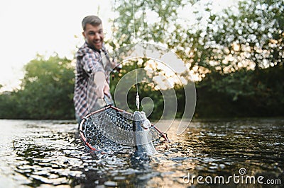 Fisherman picking up big rainbow trout from his fishing net Stock Photo