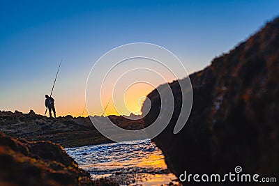Fisherman preparing his fishing rod during sunset Stock Photo