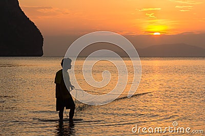 A fisherman pulls in his net at sunset on Rajamangala beach in Trang province, Thailand Editorial Stock Photo