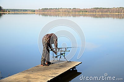 Fisherman with rod pod, feeders, electronic bite alarms on pier Stock Photo