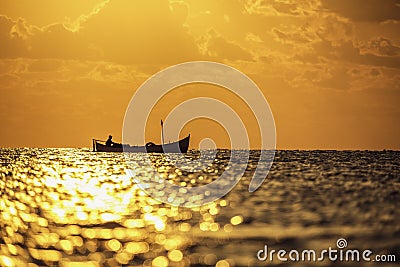 Fisherman sailling in the sea with his boat on beautiful sunrise Stock Photo