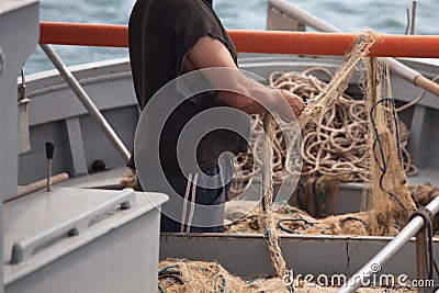 Fisherman is settings up his fishing net on the boat in the sea Stock Photo