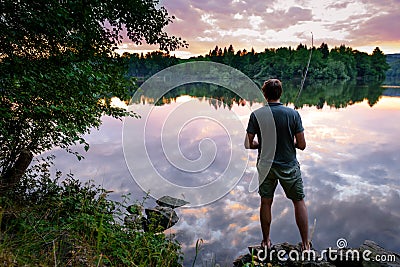 Fisherman standing on the banks of Vltava at beautiful sunset, fishing concept Stock Photo