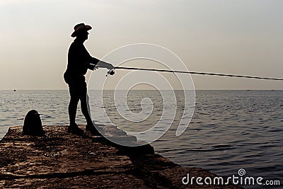 Fisherman standing on a pier at dawn sky background. Silhouette photo. Editorial Stock Photo