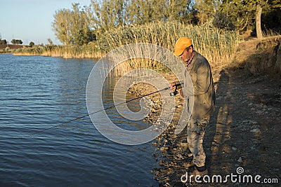 Fisherman standing on the riverside and trying to catch a fish. Sport, recreation Stock Photo