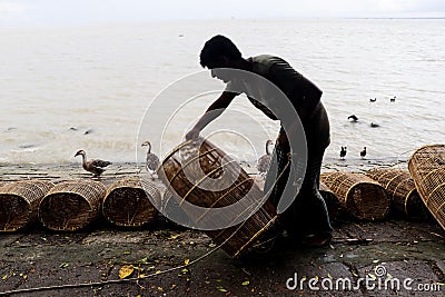 Fisherman taking preparation for fishing by cage and rope on the riverbank Editorial Stock Photo