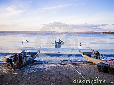 Fisherman with traditional boat returns to the coast after a fishing trip, Bolsena lakeshore, Viterbo province, Lazio, Italy Stock Photo