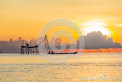 Fisherman on a traditional wooden boat during sunrise Stock Photo