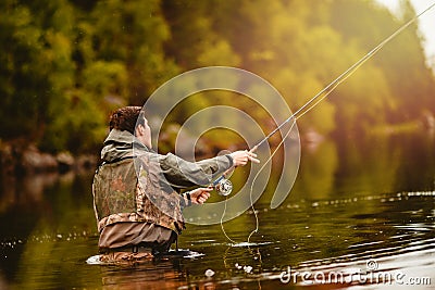 Fisherman using rod fly fishing in mountain river Stock Photo