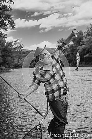 Fisherman using rod flyfishing in mountain river. Fisherman fishing on a rever. Happy old fisherman caught a trout fish Stock Photo