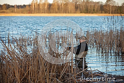 Fisherman in waders catches pike in the lake Stock Photo