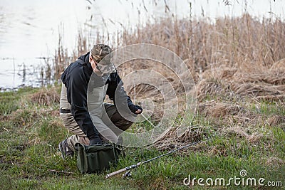 Fisherman in waders prepares bait for catching pike in the river Stock Photo