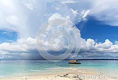 Fisherman on a wooden boat on clear blue water along a exotic be Stock Photo