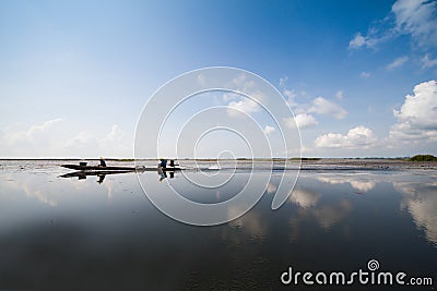 Fisherman in wooden boat crusing in the lake with reflection with cloudy blue sky background Stock Photo