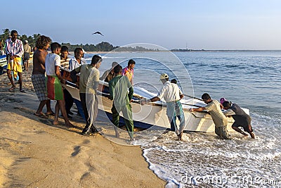 Fishermen drag a boat onto the beach. Editorial Stock Photo