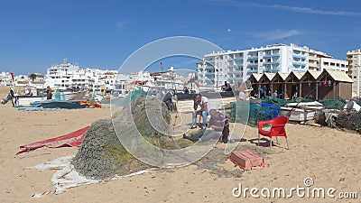 Fishermen mending their nets. At the long, wide, fine sandy fisherman beach of Armacao de Pera, Algarve, Portugal Editorial Stock Photo
