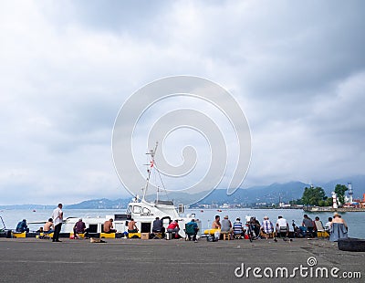 Fishermen near the ships. People at the pier. Favorite hobby. Fishing in the port. Family food. people with fishing rods Editorial Stock Photo