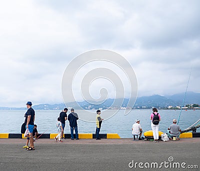 Fishermen near the ships. People at the pier. Favorite hobby. Fishing in the port. Family food. people with fishing rods Editorial Stock Photo