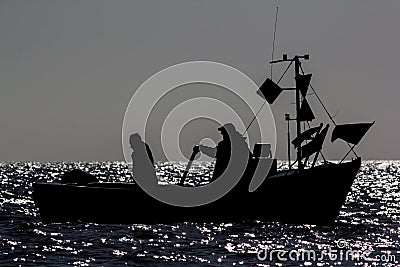 Fishermen at sea in a small fishing boat. Peaceful silhoette by Editorial Stock Photo