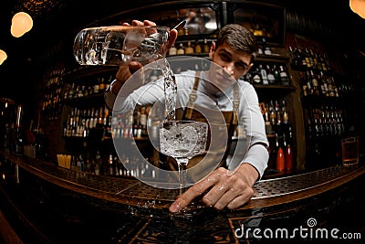 Fisheye shot attractive bartender pouring a cocktail from the measuring cup to the glass Stock Photo