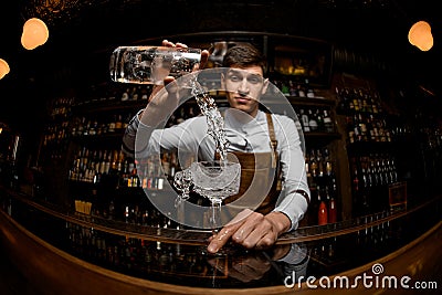 Fisheye shot professional bartender pouring a cocktail from the measuring cup to the glass Stock Photo