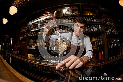 Fisheye shot smiling bartender pouring a cocktail from the measuring cup to the glass Stock Photo